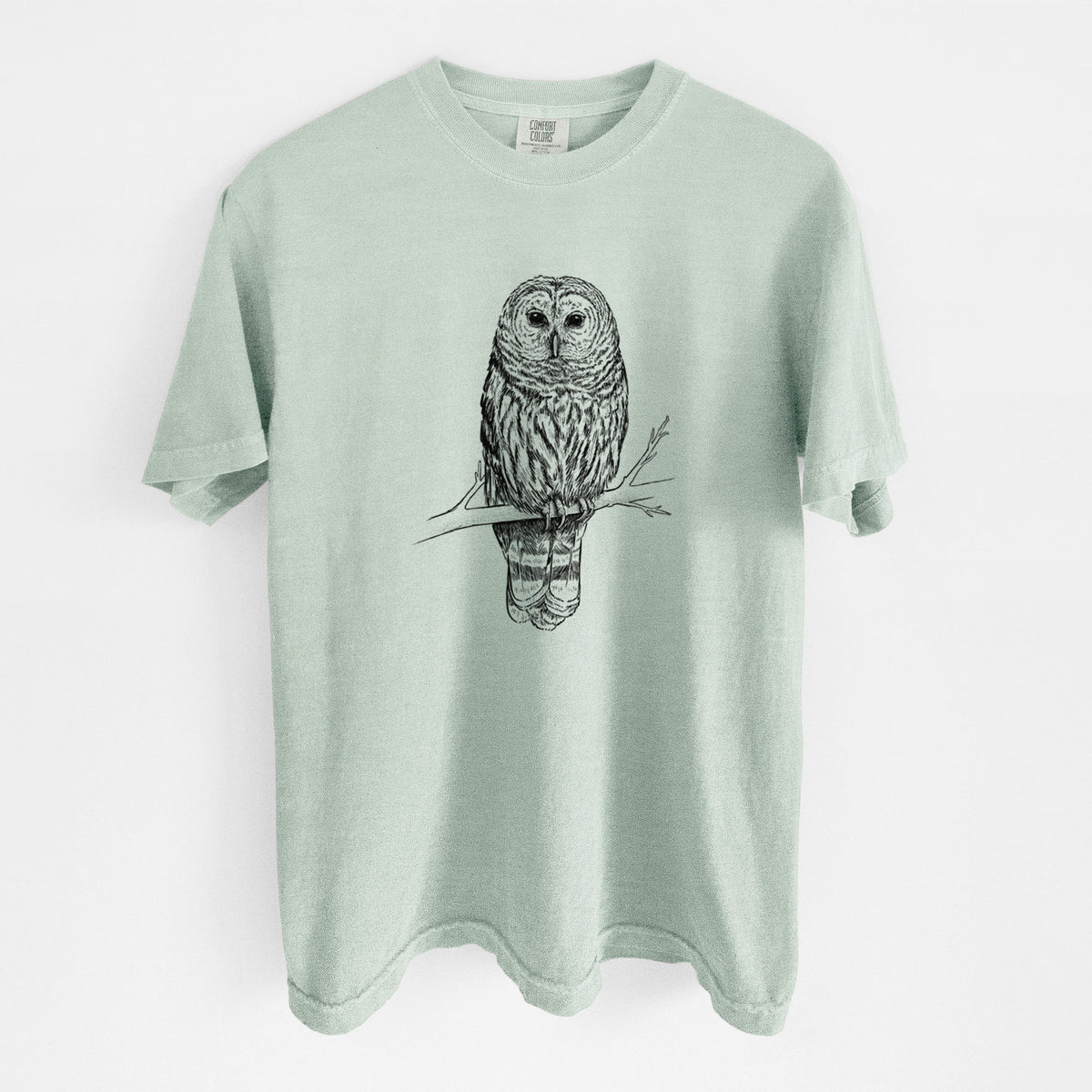 Bay green Comfort Colors t-shirt laid flat, printed with a detailed black ink illustration of a barred owl perched on a branch.