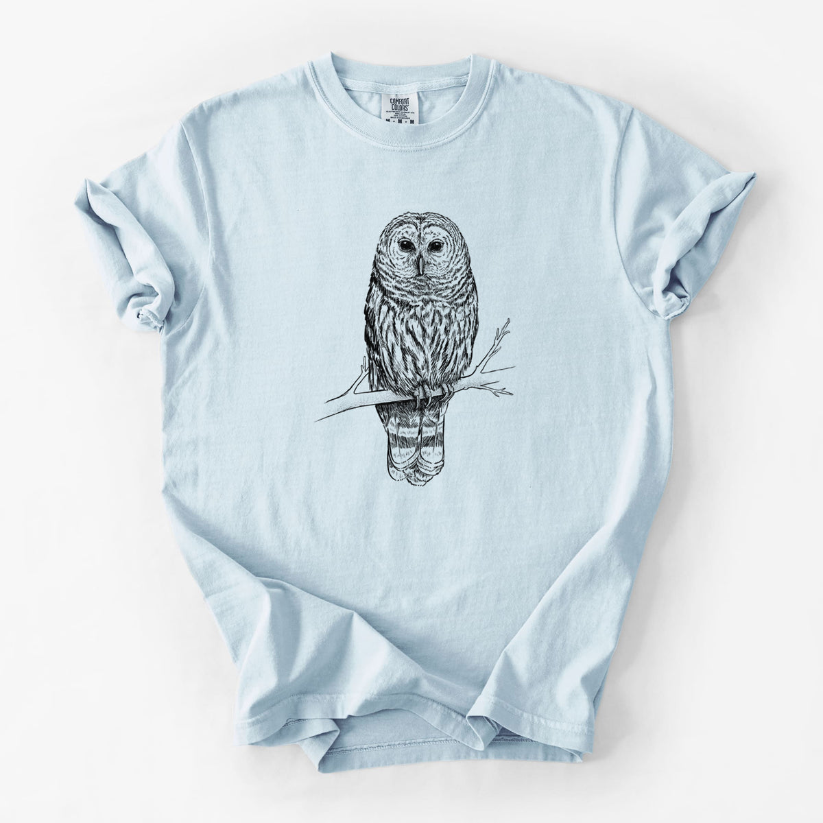 Chambray blue Comfort Colors t-shirt laid flat, printed with a detailed black ink illustration of a barred owl perched on a branch.