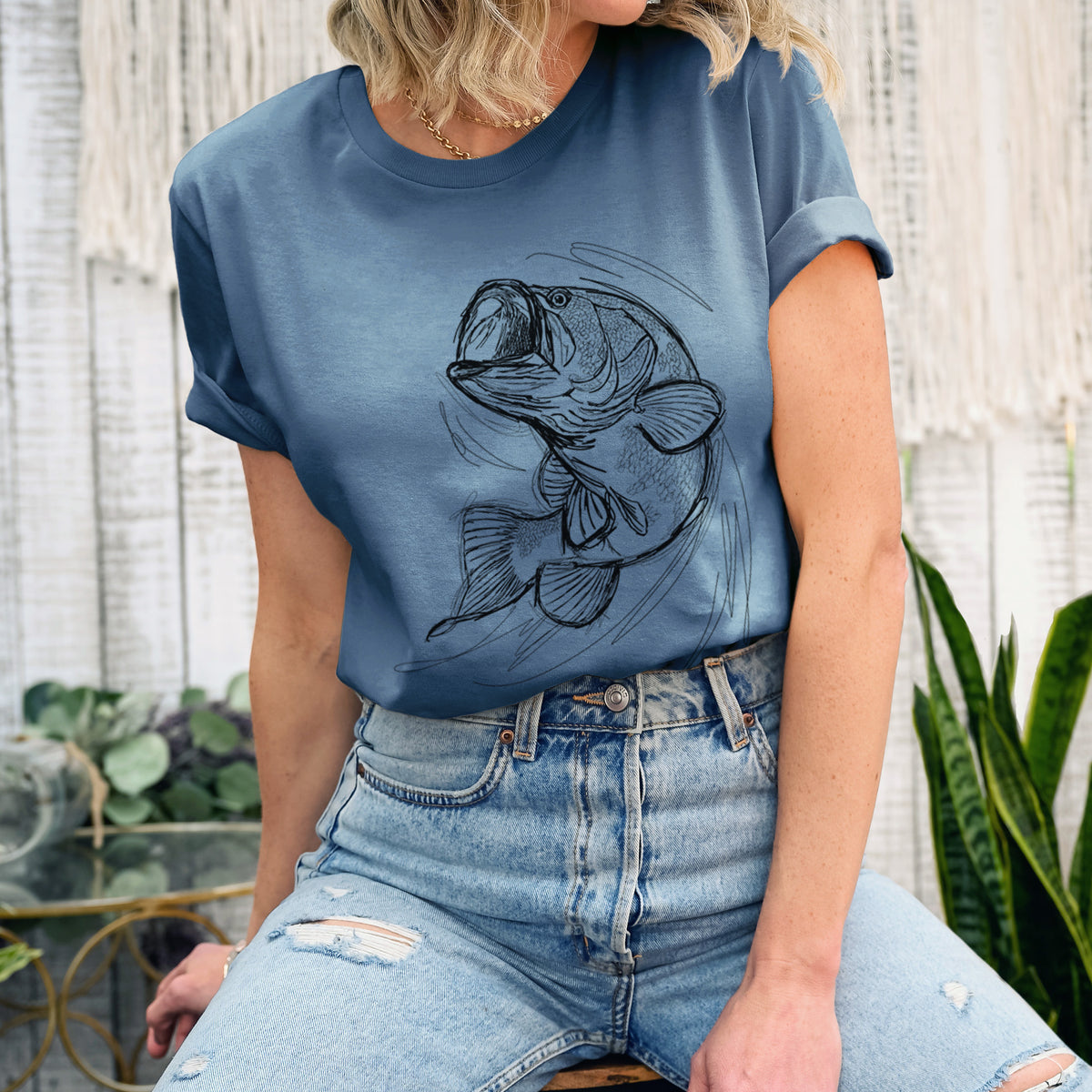 Woman wearing a steel blue lightweight cotton t-shirt printed with a detailed black ink illustration of a largemouth bass leaping with its mouth open.