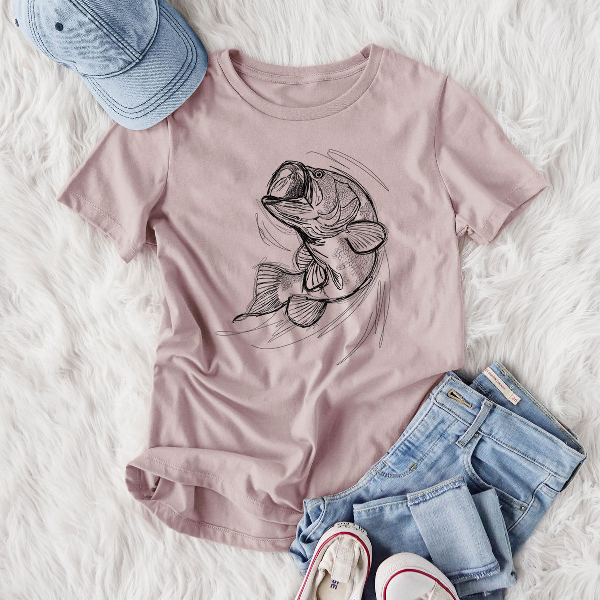 Women's relaxed fit cotton t-shirt printed with a detailed black ink illustration of a largemouth bass leaping with its mouth open, styled flat on a white faux fur rug with jeans.