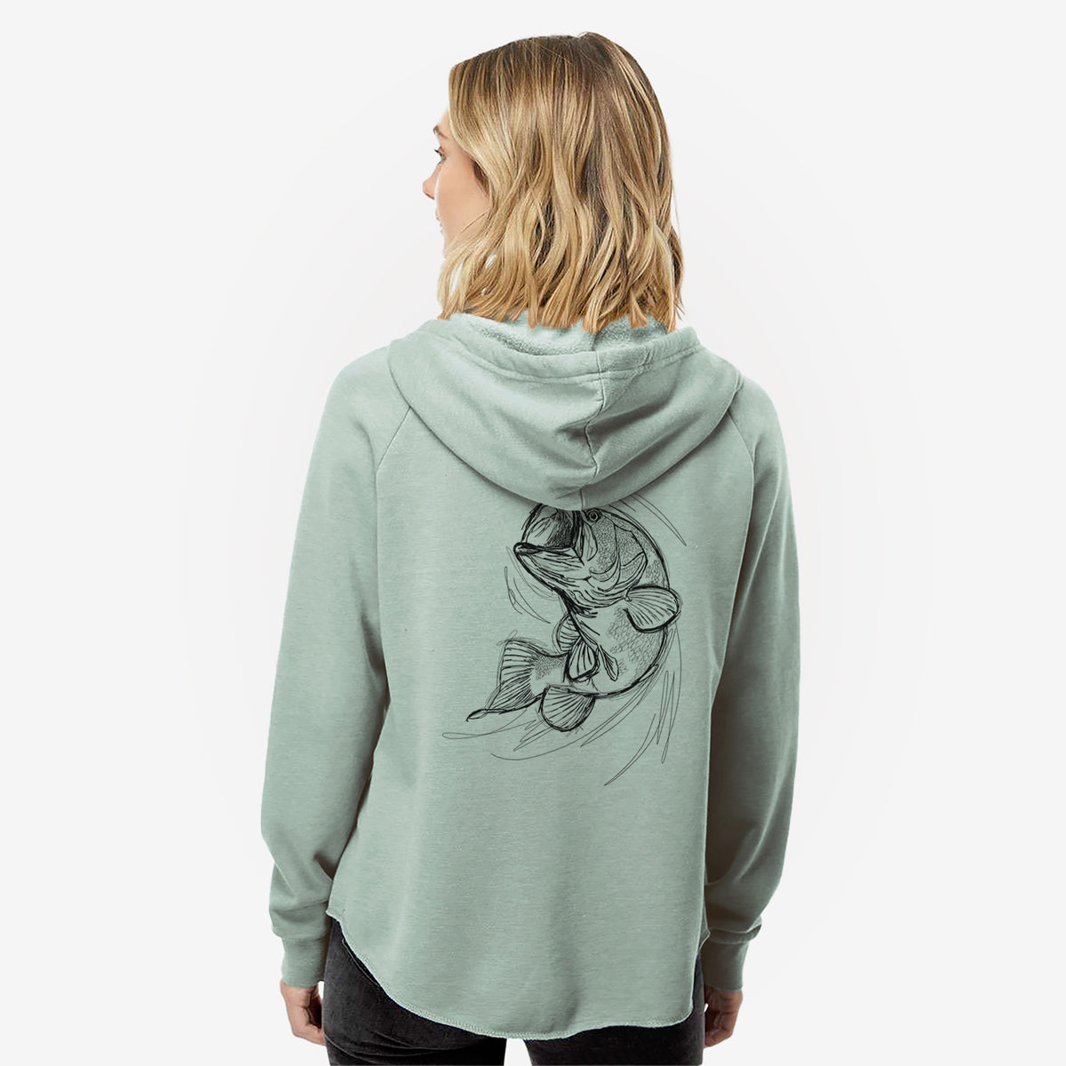 Woman wearing a sage green women's Cali Wave zip-up sweatshirt printed with a detailed black ink illustration of a largemouth bass leaping with its mouth open, seen from behind.