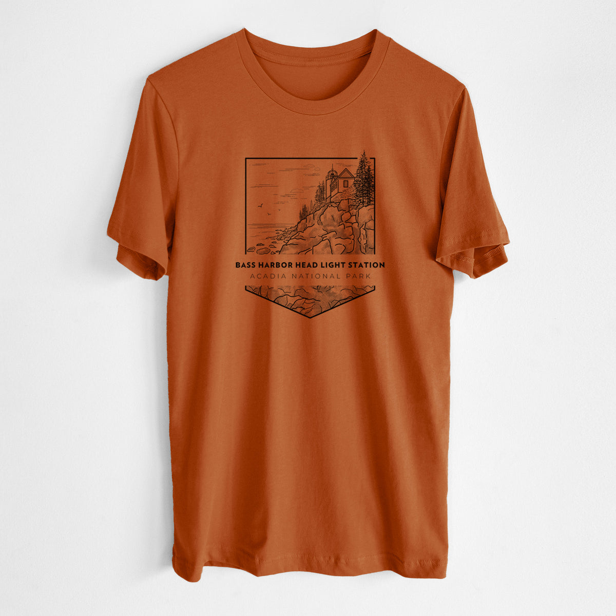 Autumn lightweight cotton t-shirt laid flat, printed with a black line art badge of Bass Harbor Head Light Station on a rocky cliff, with the words Acadia National Park.