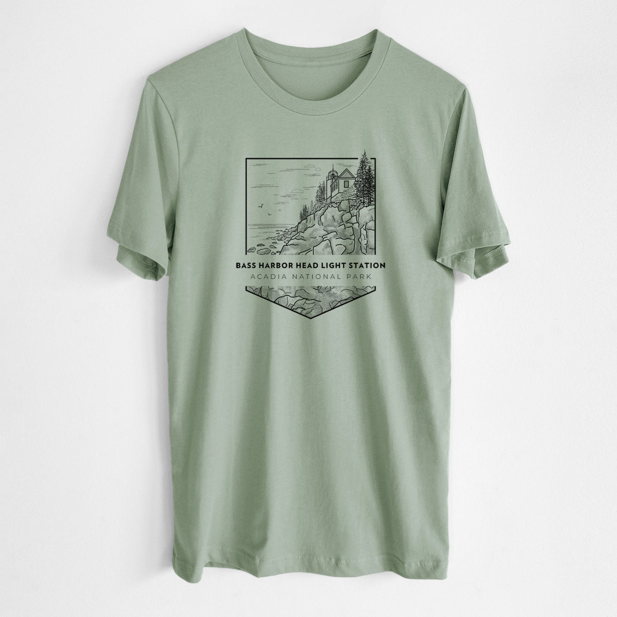 Sage green lightweight cotton t-shirt laid flat, printed with a black line art badge of Bass Harbor Head Light Station on a rocky cliff, with the words Acadia National Park.
