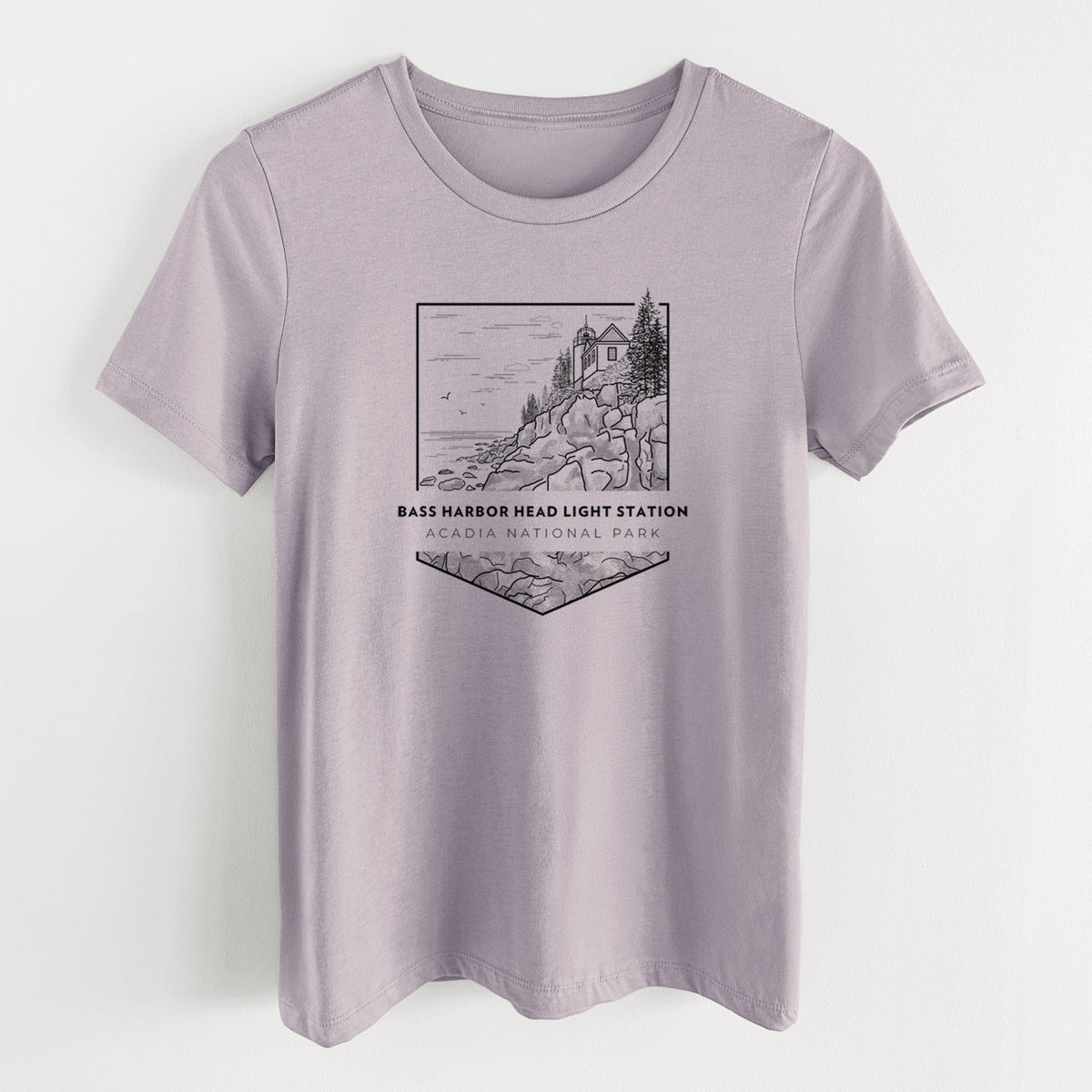Light violet women's relaxed fit cotton t-shirt laid flat, printed with a black line art badge of Bass Harbor Head Light Station on a rocky cliff, with the words Acadia National Park.