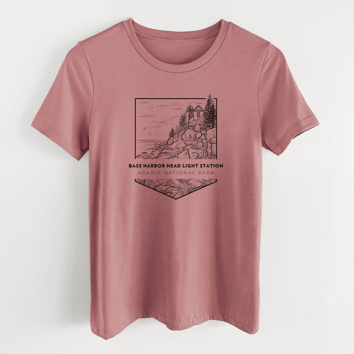 Mauve pink women's relaxed fit cotton t-shirt laid flat, printed with a black line art badge of Bass Harbor Head Light Station on a rocky cliff, with the words Acadia National Park.