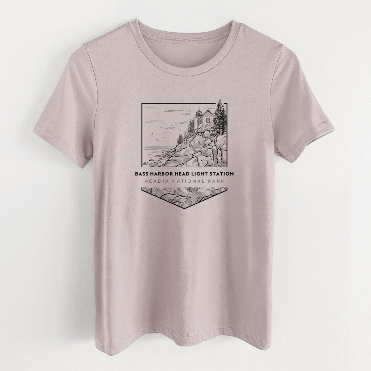 Pink gravel women's relaxed fit cotton t-shirt laid flat, printed with a black line art badge of Bass Harbor Head Light Station on a rocky cliff, with the words Acadia National Park.