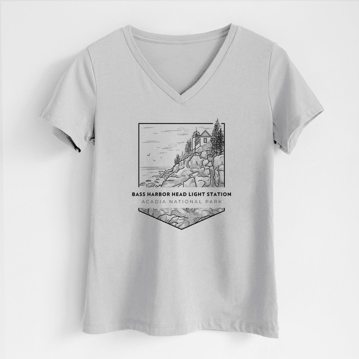 Lunar grey women's relaxed fit cotton V-neck t-shirt laid flat, printed with a black line art badge of Bass Harbor Head Light Station on a rocky cliff, with the words Acadia National Park.