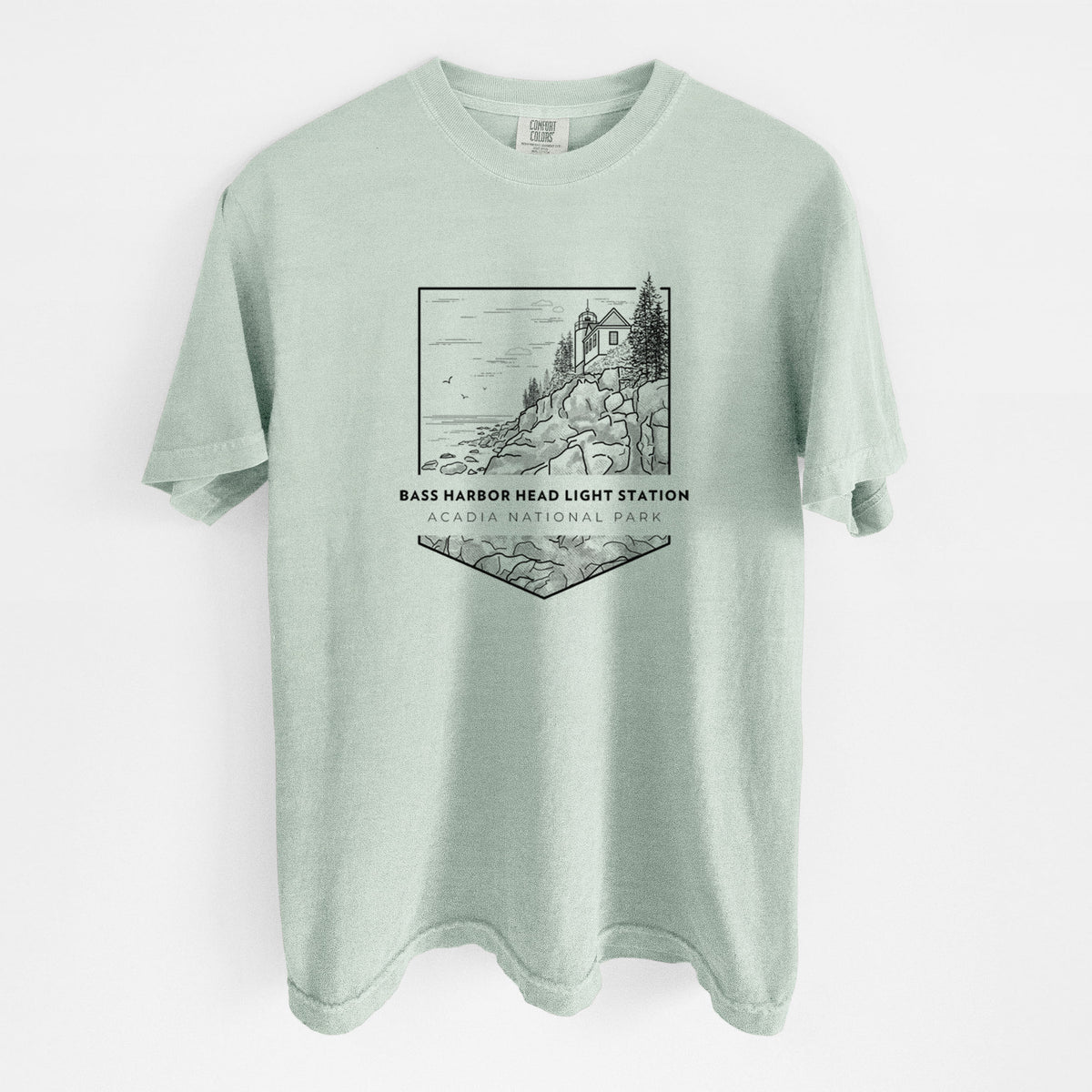 Bay green Comfort Colors t-shirt laid flat, printed with a black line art badge of Bass Harbor Head Light Station on a rocky cliff, with the words Acadia National Park.