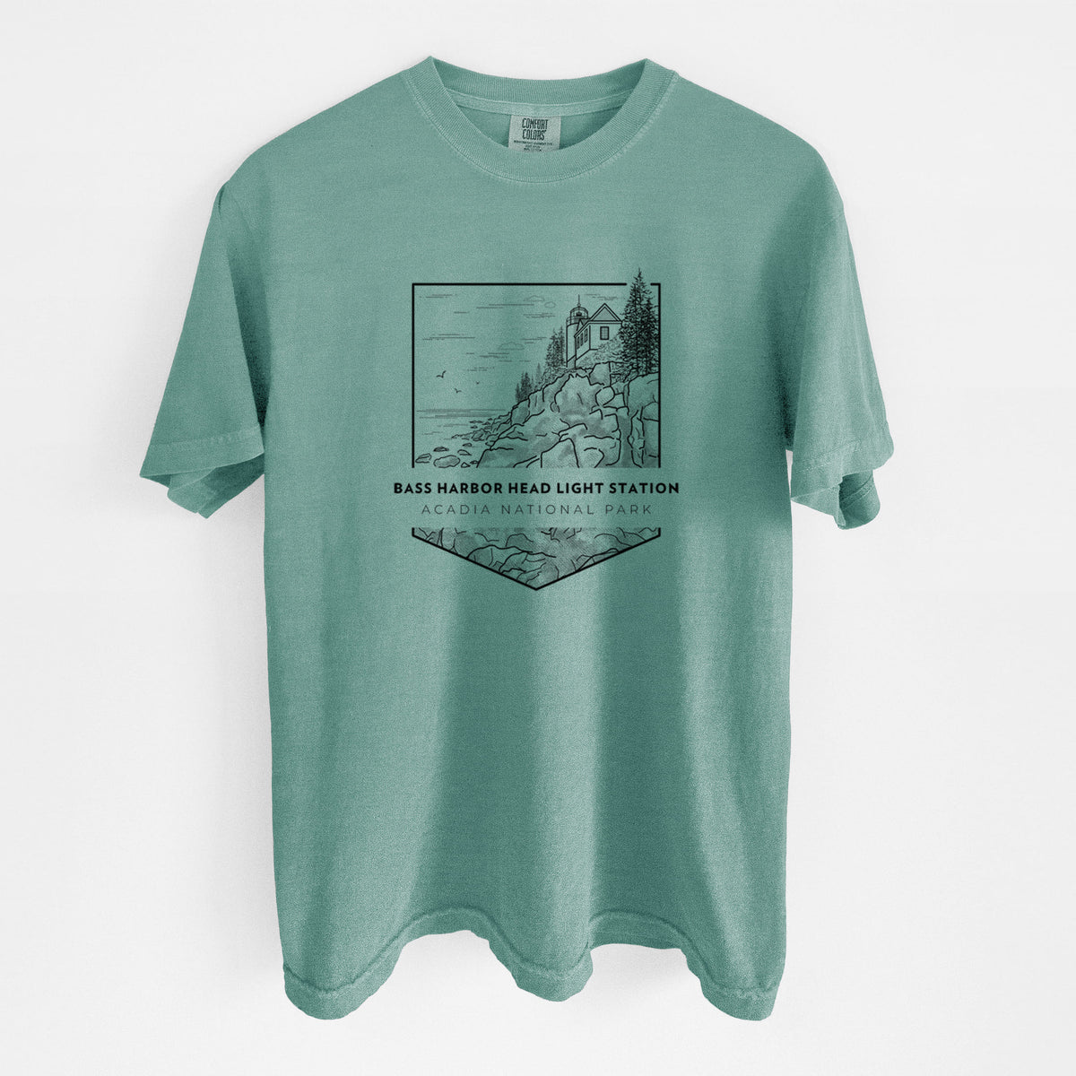 Reef green Comfort Colors t-shirt laid flat, printed with a black line art badge of Bass Harbor Head Light Station on a rocky cliff, with the words Acadia National Park.