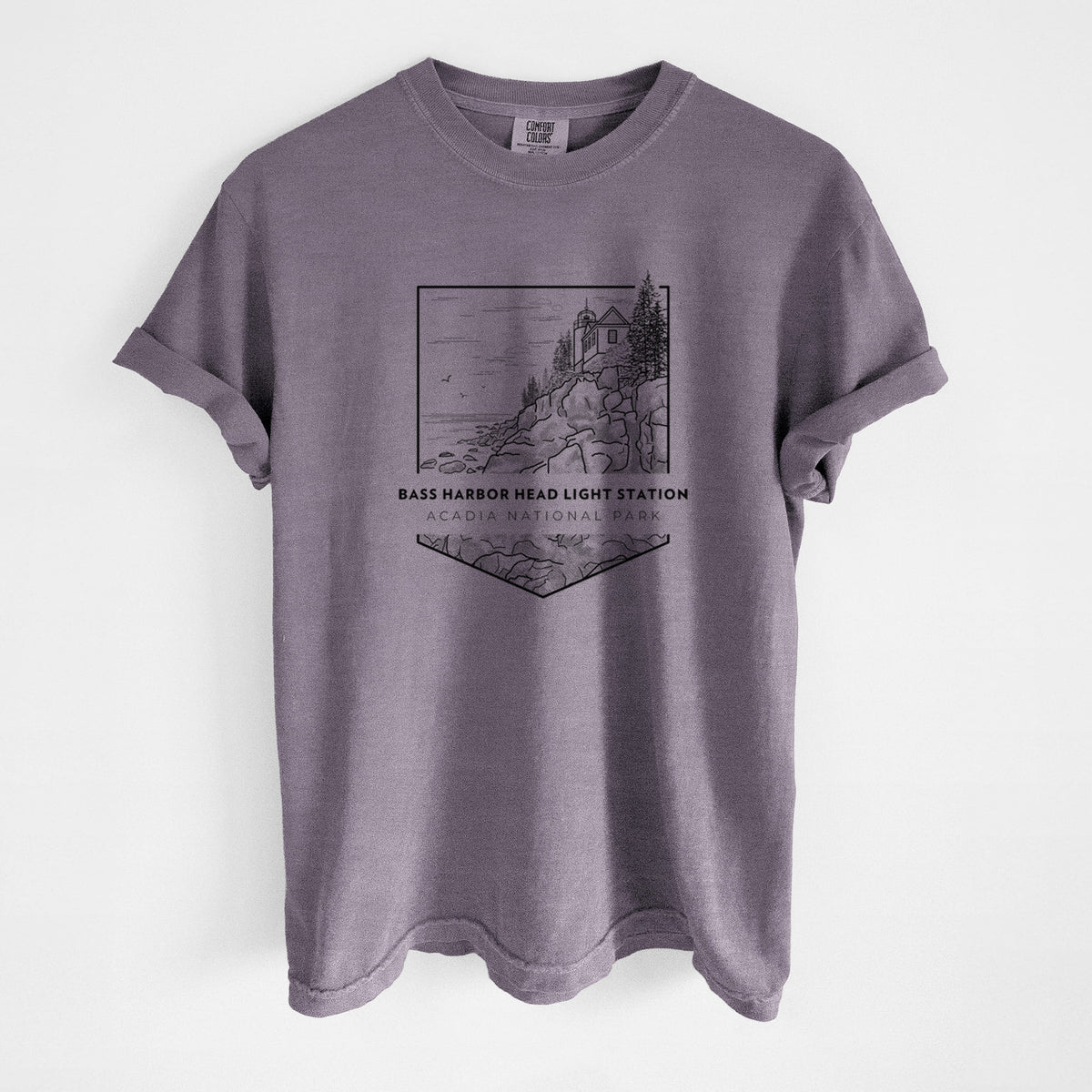 Wine red Comfort Colors t-shirt laid flat, printed with a black line art badge of Bass Harbor Head Light Station on a rocky cliff, with the words Acadia National Park.