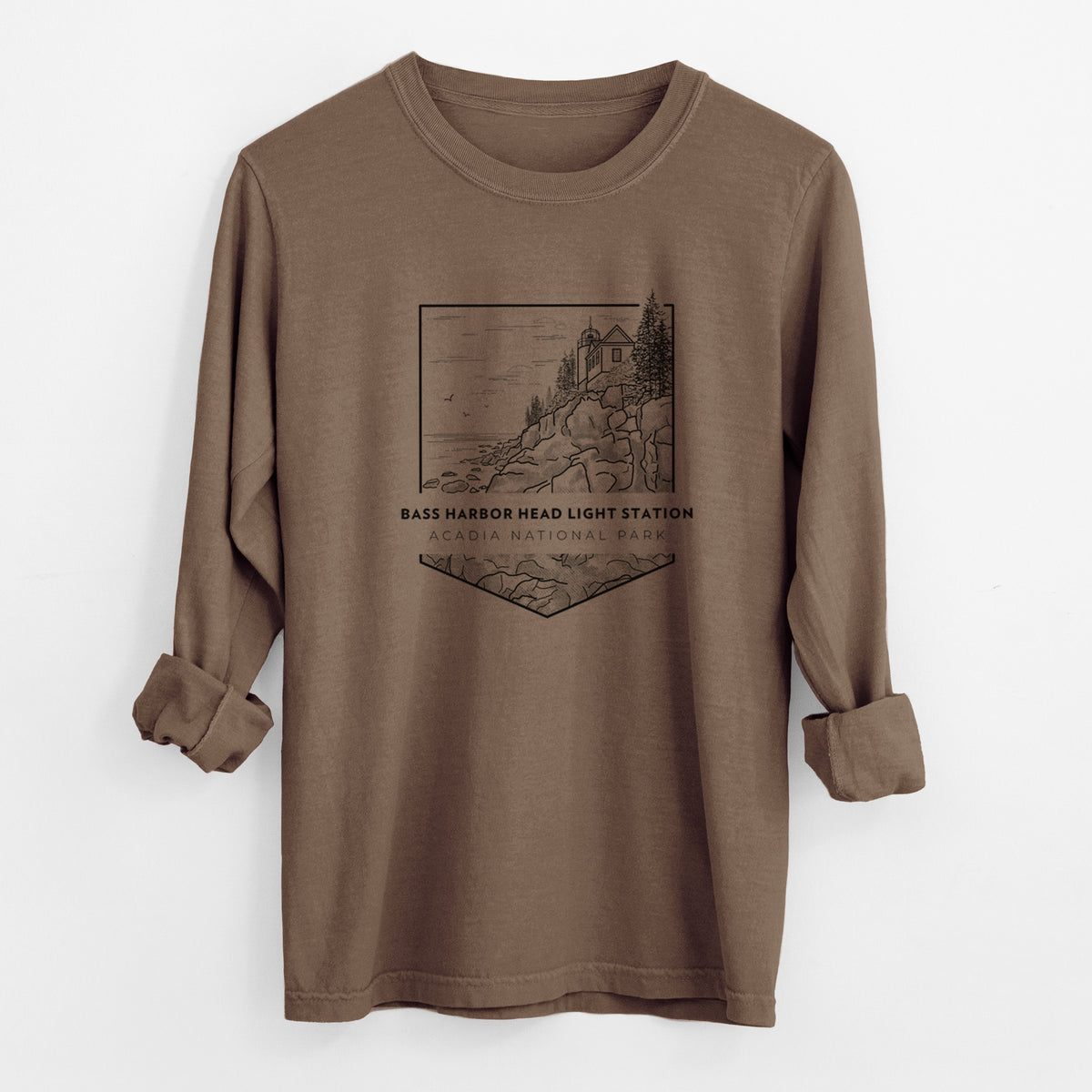 Espresso brown Comfort Colors long sleeve shirt laid flat with the cuffs rolled, printed with a black line art badge of Bass Harbor Head Light Station on a rocky cliff, with the words Acadia National Park.