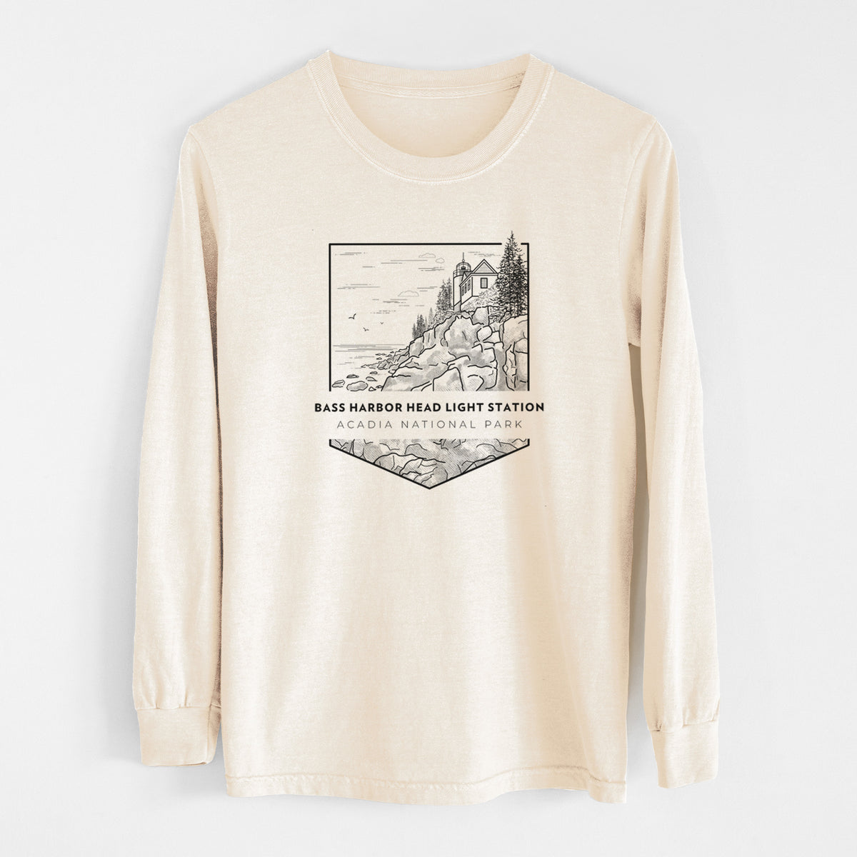 Ivory Comfort Colors long sleeve shirt laid flat, printed with a black line art badge of Bass Harbor Head Light Station on a rocky cliff, with the words Acadia National Park.