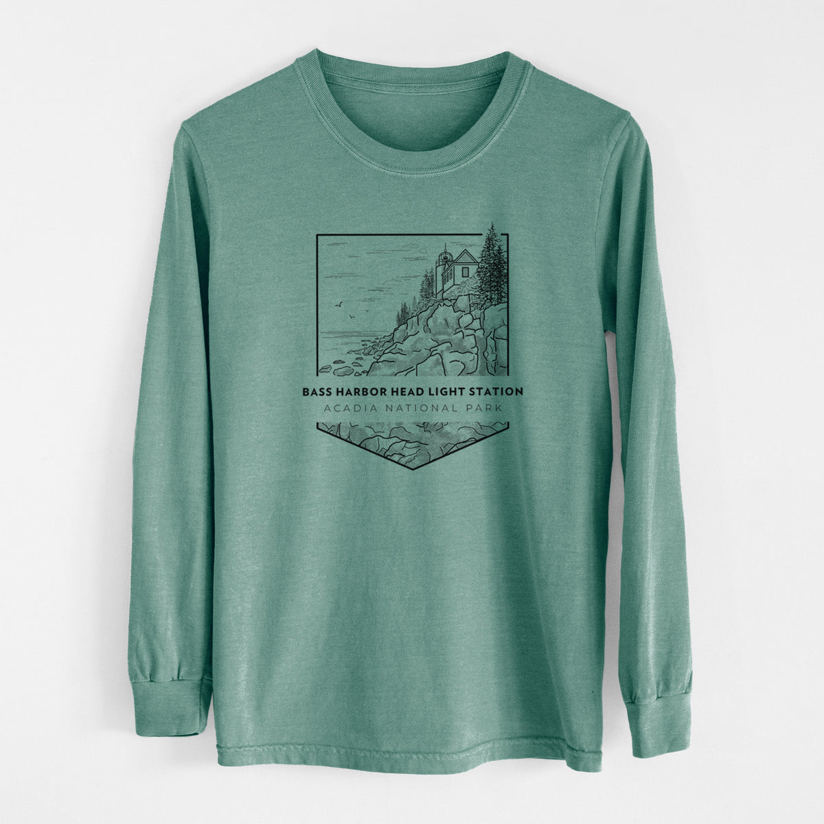 Pine green Comfort Colors long sleeve shirt laid flat, printed with a black line art badge of Bass Harbor Head Light Station on a rocky cliff, with the words Acadia National Park.