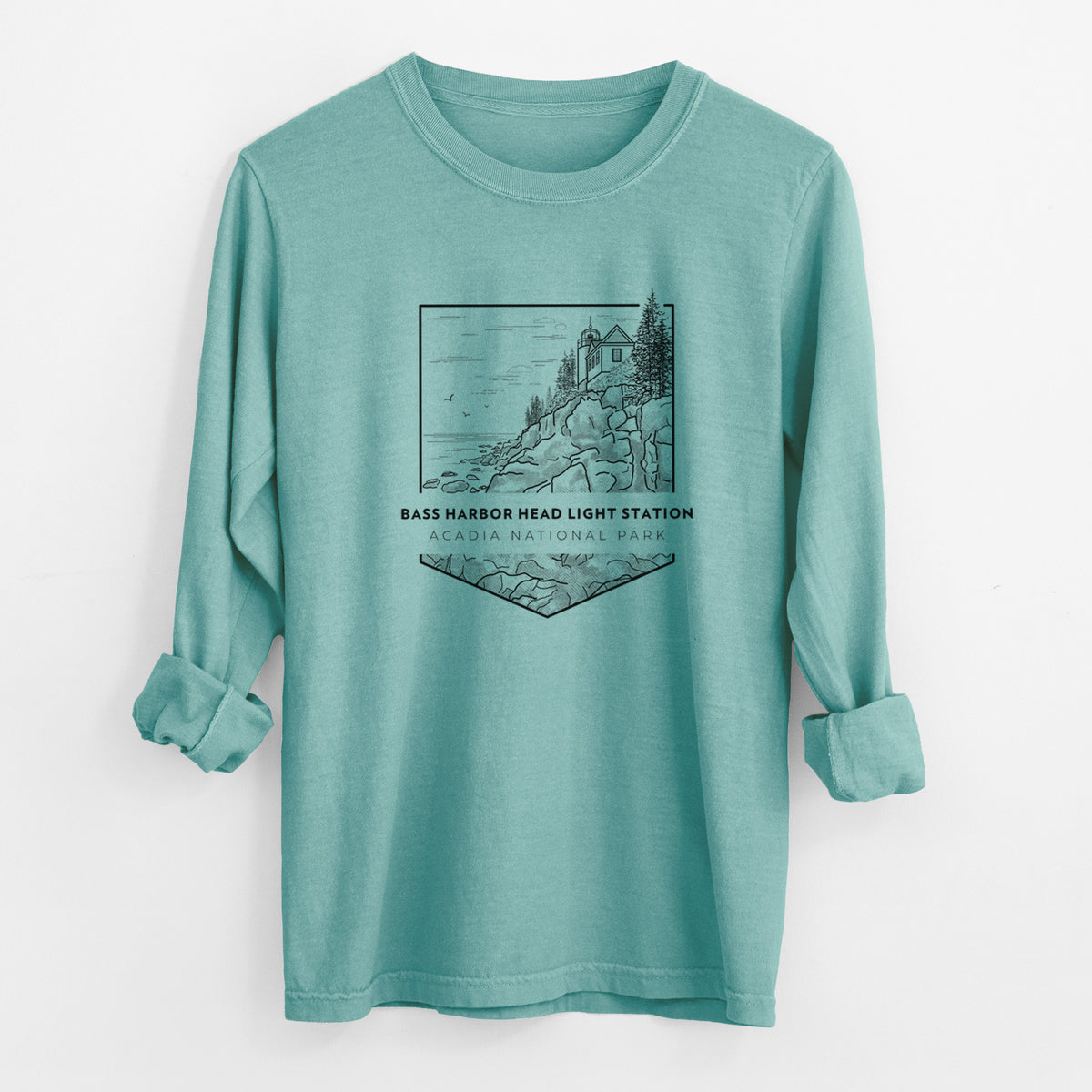 Reef green Comfort Colors long sleeve shirt laid flat with the cuffs rolled, printed with a black line art badge of Bass Harbor Head Light Station on a rocky cliff, with the words Acadia National Park.
