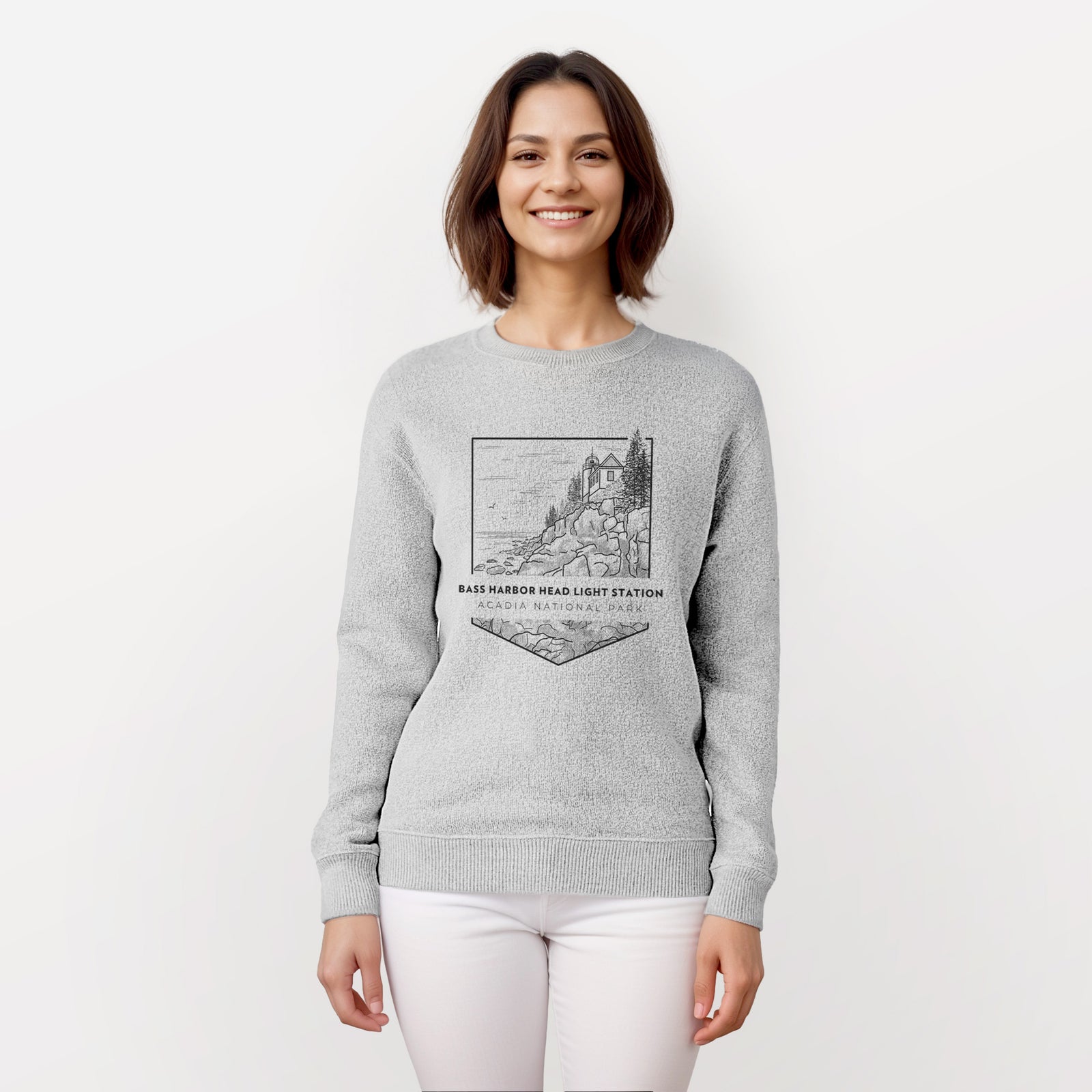 Salt and pepper knit sweatshirt laid flat, printed with a black line art badge of Bass Harbor Head Light Station on a rocky cliff, with the words Acadia National Park.