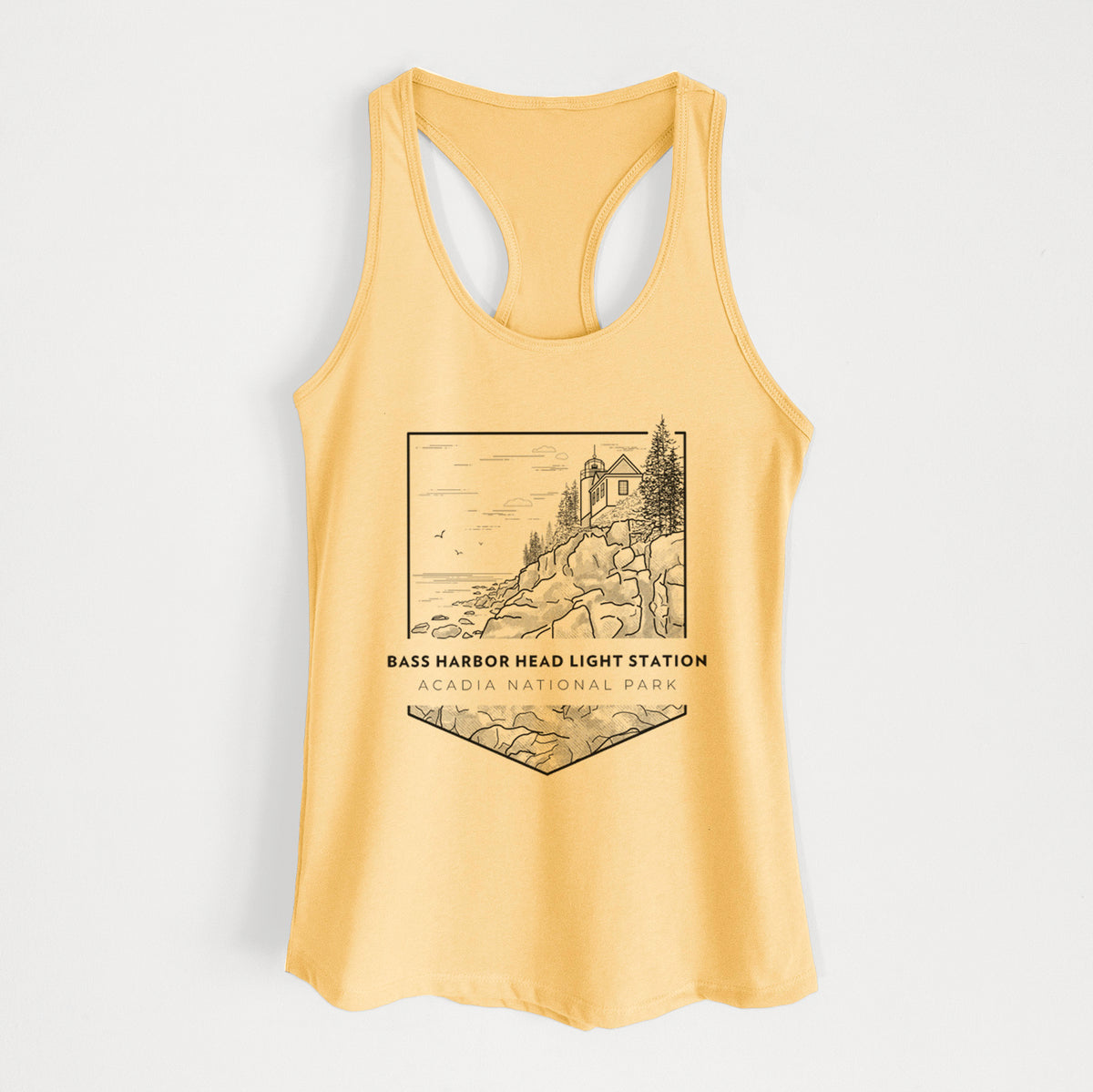 Banana cream women's racerback tank top laid flat, printed with a black line art badge of Bass Harbor Head Light Station on a rocky cliff, with the words Acadia National Park.