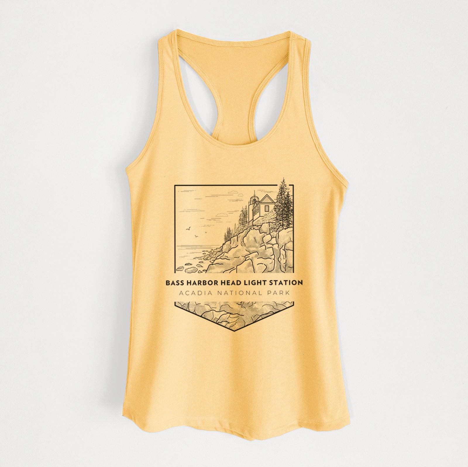 Banana cream women's racerback tank top laid flat, printed with a black line art badge of Bass Harbor Head Light Station on a rocky cliff, with the words Acadia National Park.