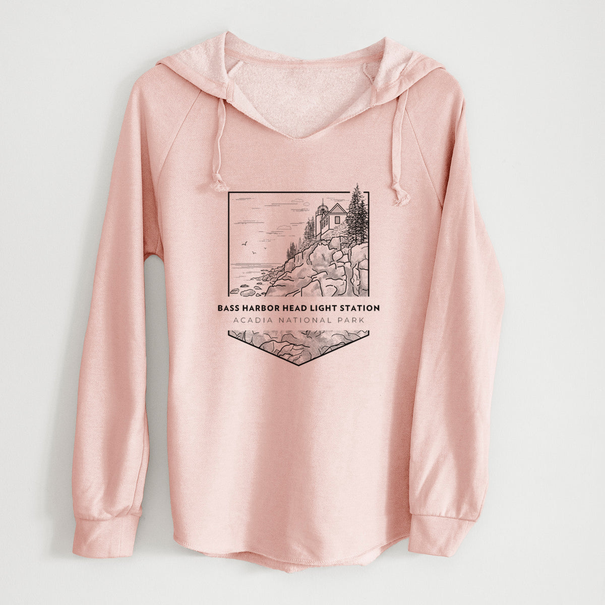 Blush pink women's Cali Wave hooded sweatshirt laid flat, printed with a black line art badge of Bass Harbor Head Light Station on a rocky cliff, with the words Acadia National Park.