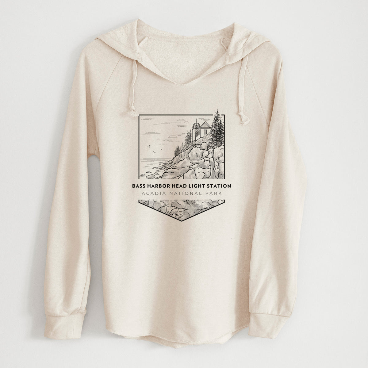 Bone cream women's Cali Wave hooded sweatshirt laid flat, printed with a black line art badge of Bass Harbor Head Light Station on a rocky cliff, with the words Acadia National Park.