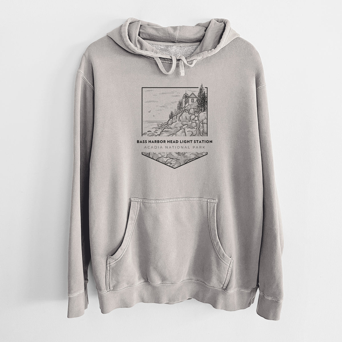 Cement grey pigment dyed hoodie laid flat, printed with a black line art badge of Bass Harbor Head Light Station on a rocky cliff, with the words Acadia National Park.