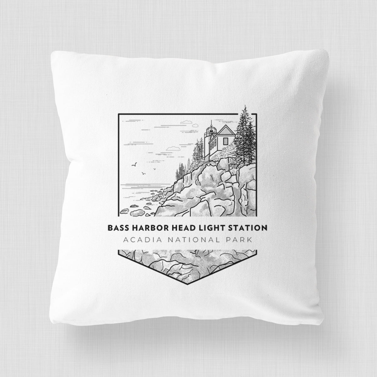 White pillow cover printed with a black line art badge of Bass Harbor Head Light Station on a rocky cliff, with the words Acadia National Park.
