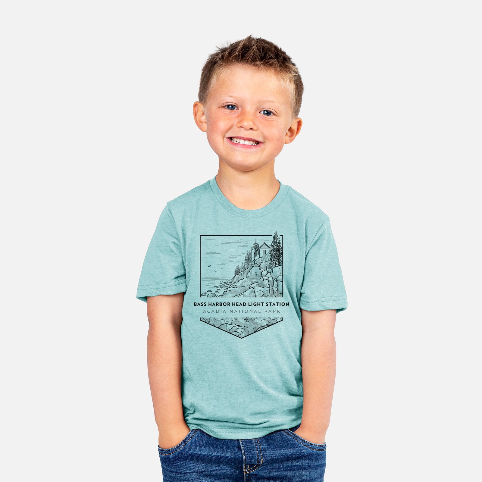 Two youth t-shirts in different colors on hangers, printed with a black line art badge of Bass Harbor Head Light Station on a rocky cliff, with the words Acadia National Park.
