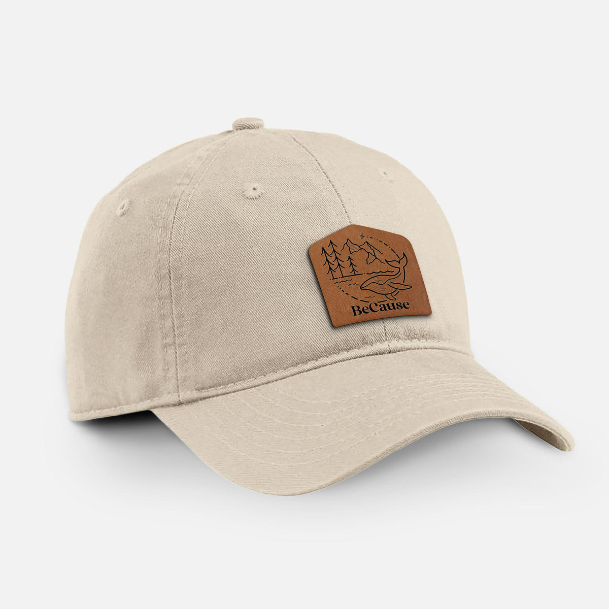 Stone cotton baseball hat with a brown leather patch engraved with a mountain landscape and the BeCause logo on the front.