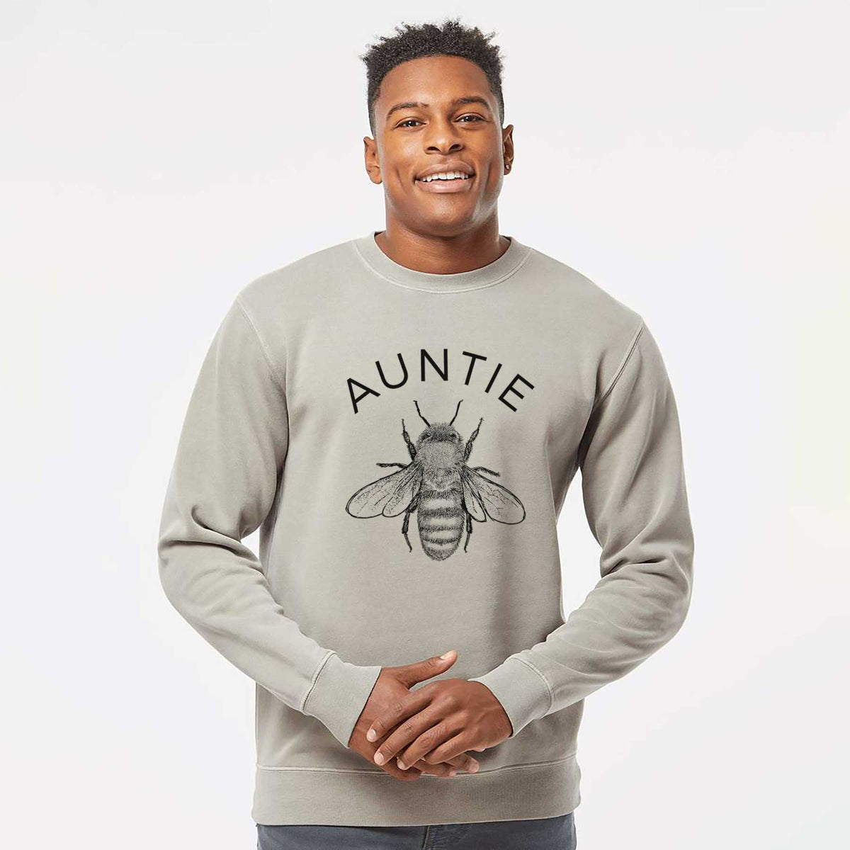 Model wearing a cement grey pigment dyed crewneck sweatshirt printed with a black ink honey bee beneath the word Auntie.