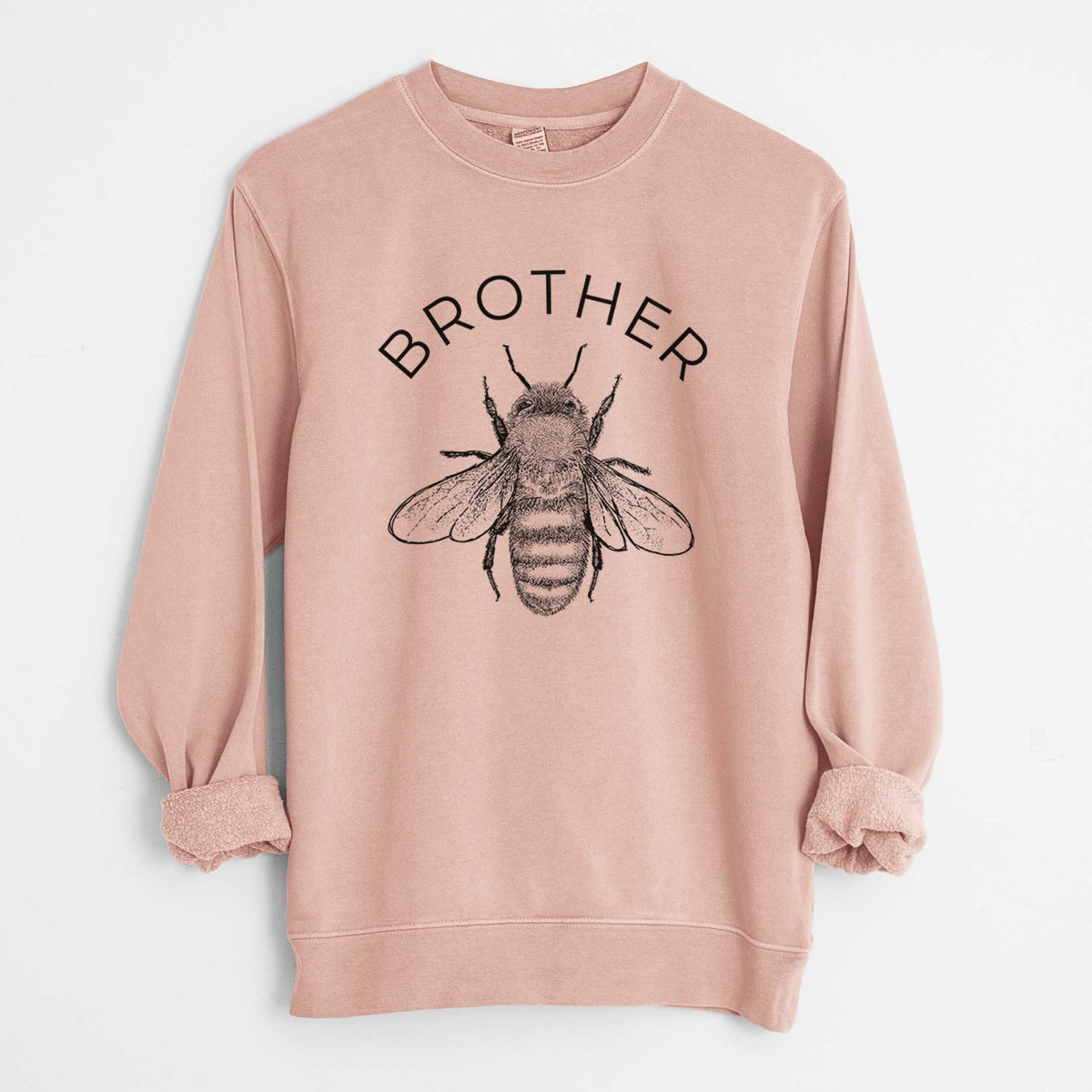 Dusty pink pigment dyed crewneck sweatshirt laid flat with the sleeves rolled, printed with a black ink honey bee beneath the word Brother.