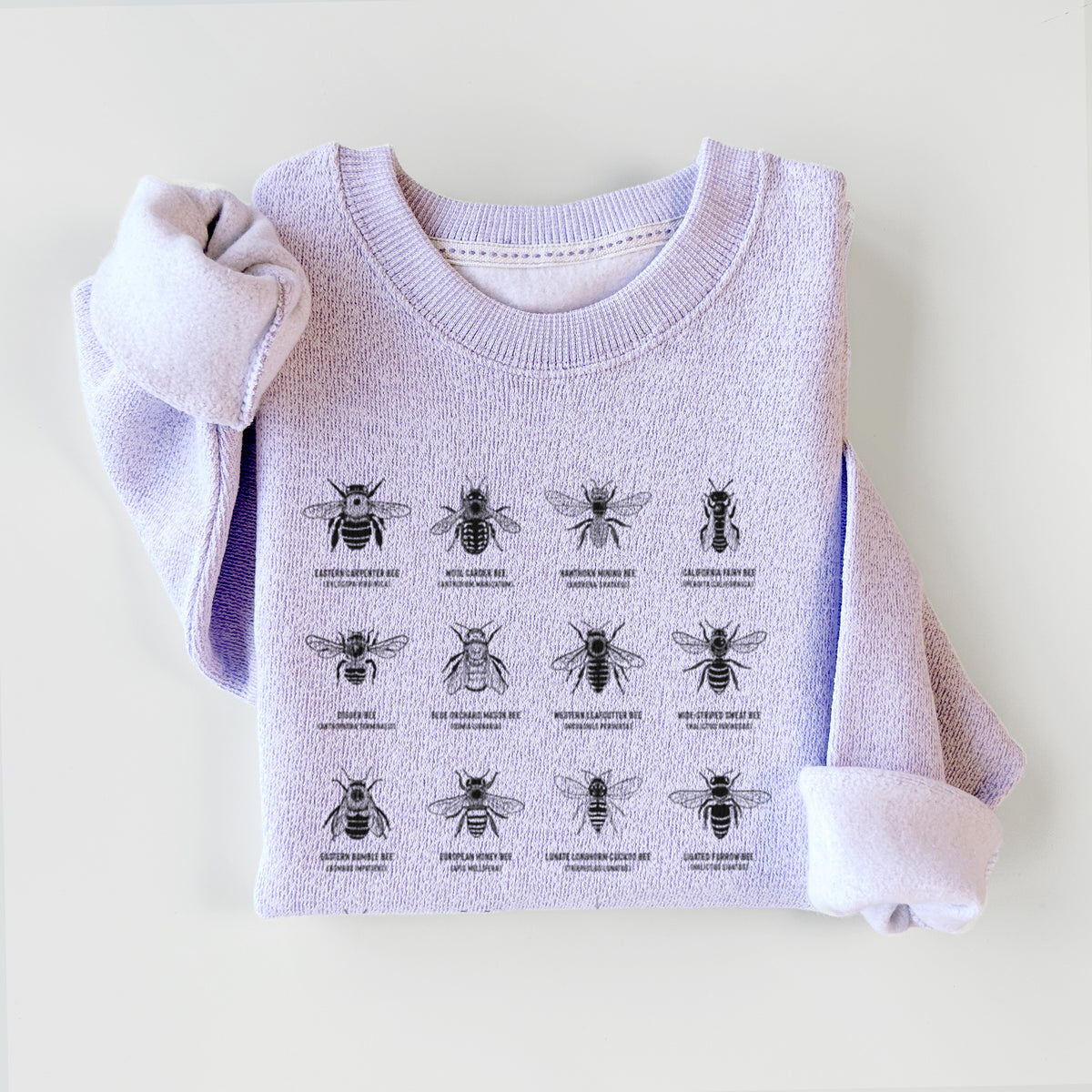 Ice purple knit sweatshirt printed with a chart of black ink illustrations of different bee species with their names, styled flat.