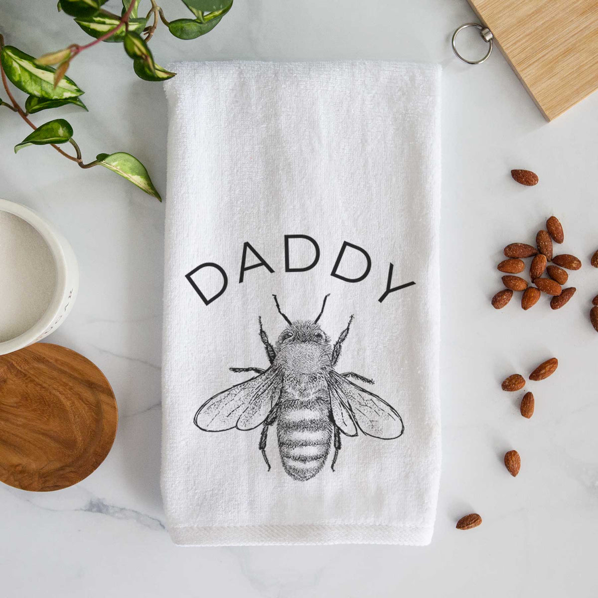 White hand towel printed with a black ink honey bee beneath the word Daddy.