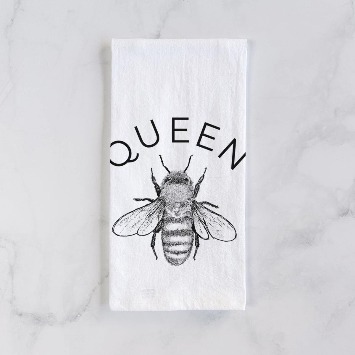 White cotton tea towel laid flat on marble, printed with a black ink honey bee beneath the word Queen.