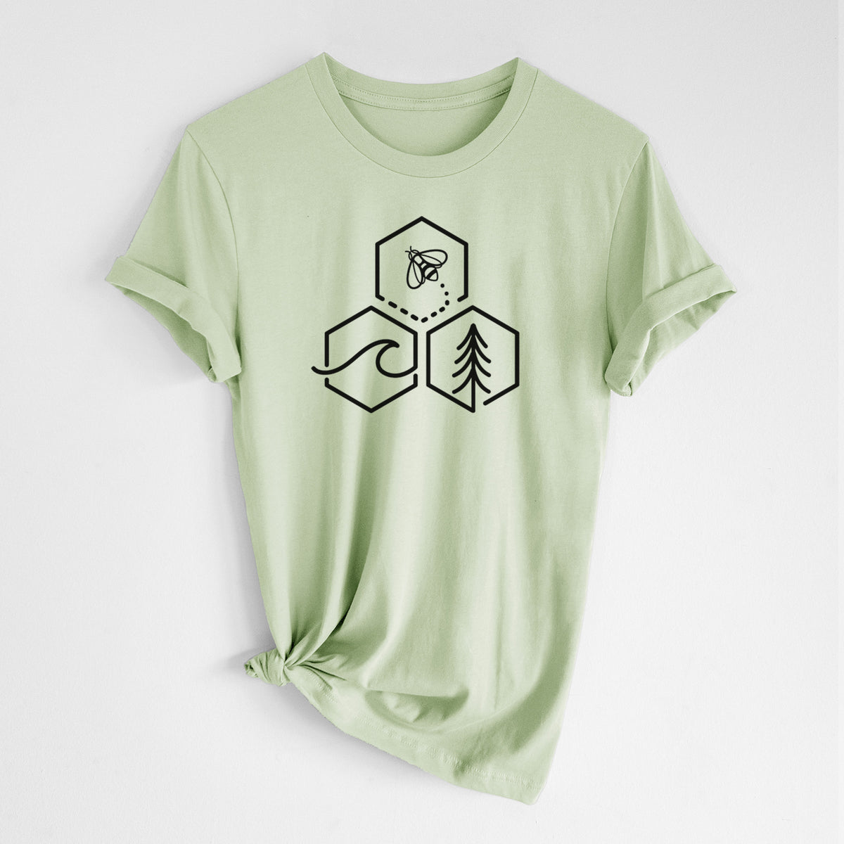 Spring green lightweight cotton t-shirt laid flat with the sleeves rolled, printed with a black line art design of three hexagons holding a bee, an ocean wave and a pine tree.