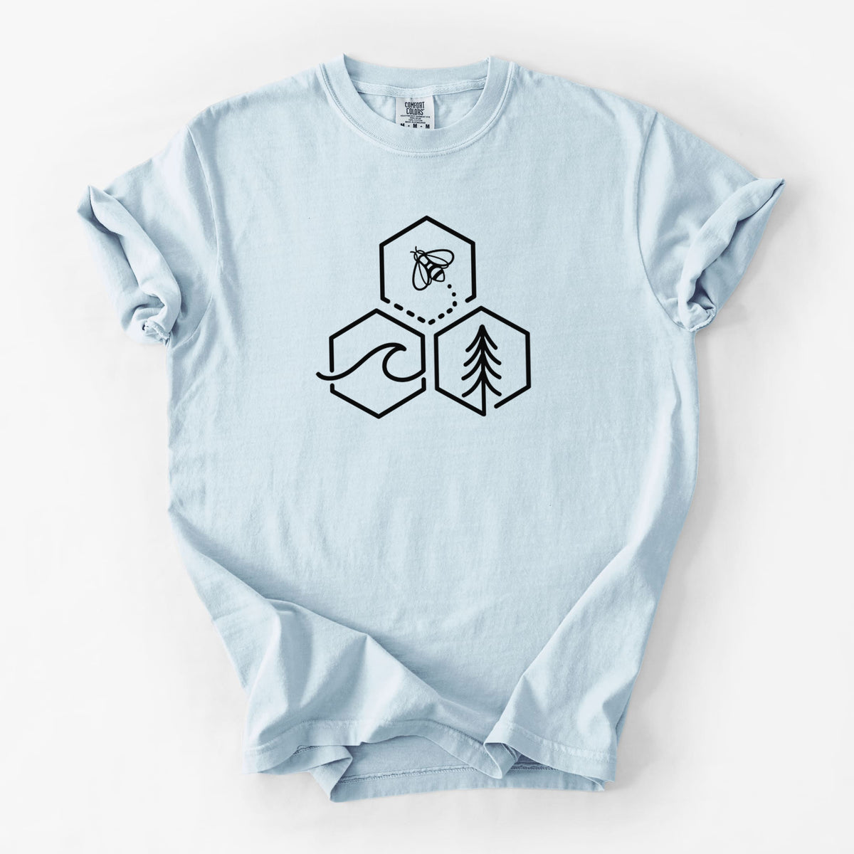 Chambray blue Comfort Colors t-shirt laid flat, printed with a black line art design of three hexagons holding a bee, an ocean wave and a pine tree.