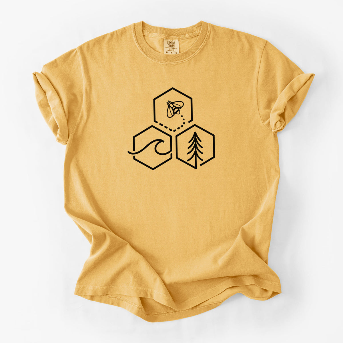 Golden wheat yellow Comfort Colors t-shirt laid flat, printed with a black line art design of three hexagons holding a bee, an ocean wave and a pine tree.
