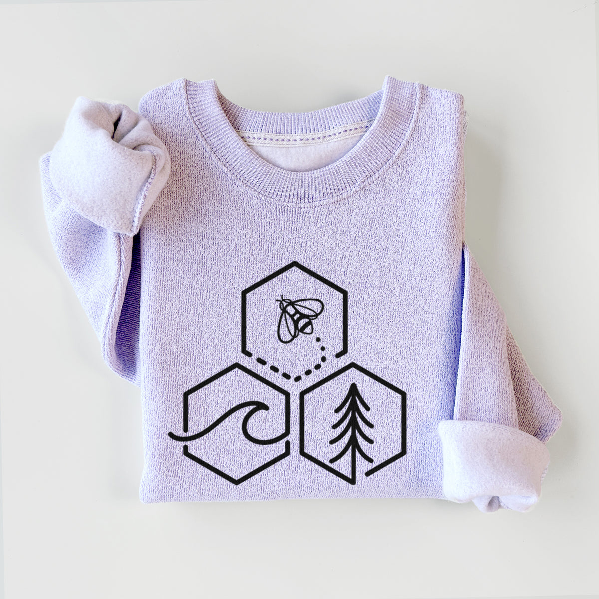Ice purple knit sweatshirt printed with a black line art design of three hexagons holding a bee, an ocean wave and a pine tree, styled flat.