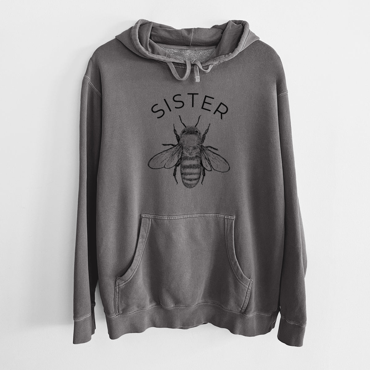 Faded black pigment dyed hoodie laid flat, printed with a black ink honey bee beneath the word Sister.