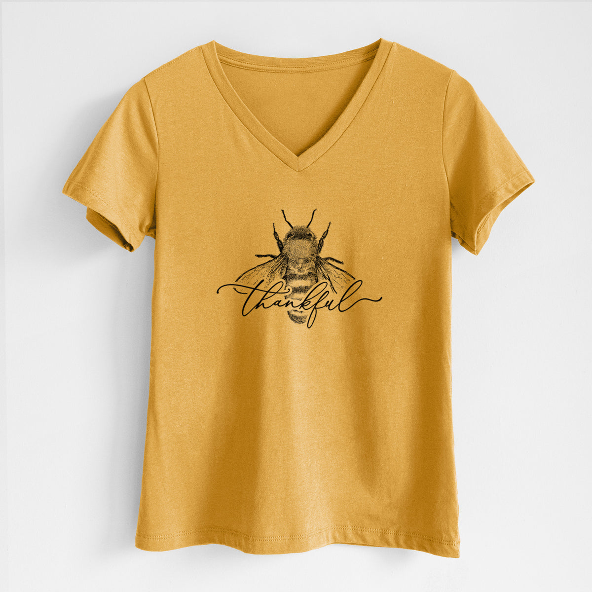 Honeycomb yellow women's relaxed fit cotton V-neck t-shirt laid flat, printed with a black ink bee with the word thankful written in script across it.