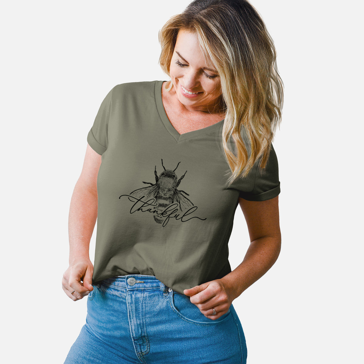 Woman wearing a military green women's relaxed fit cotton V-neck t-shirt printed with a black ink bee with the word thankful written in script across it.