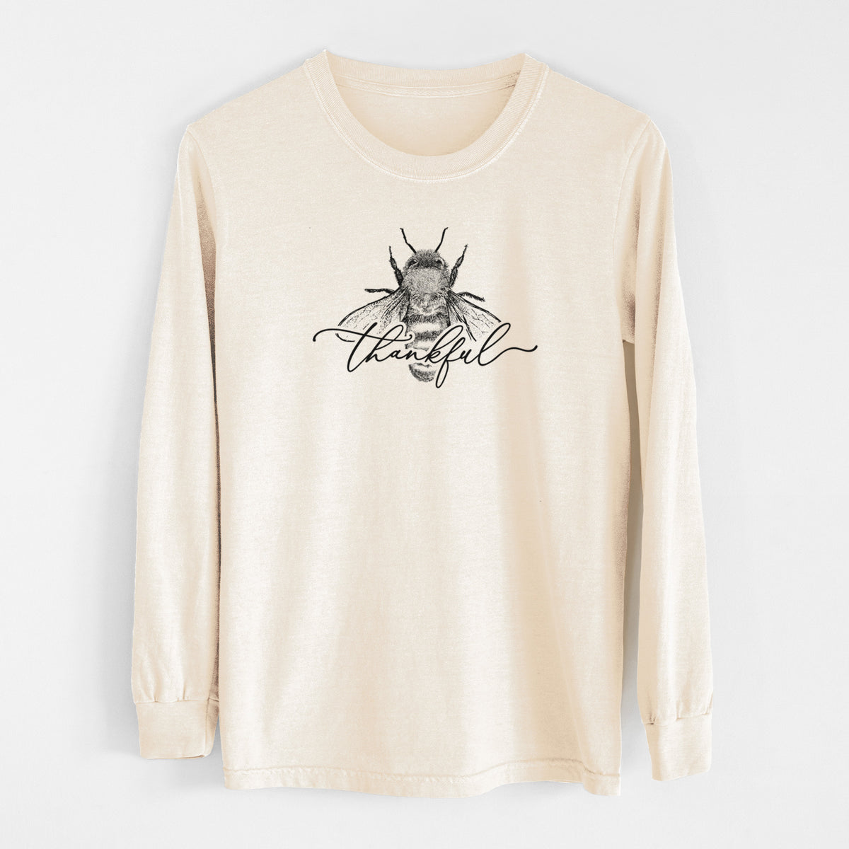 Ivory Comfort Colors long sleeve shirt laid flat, printed with a black ink bee with the word thankful written in script across it.