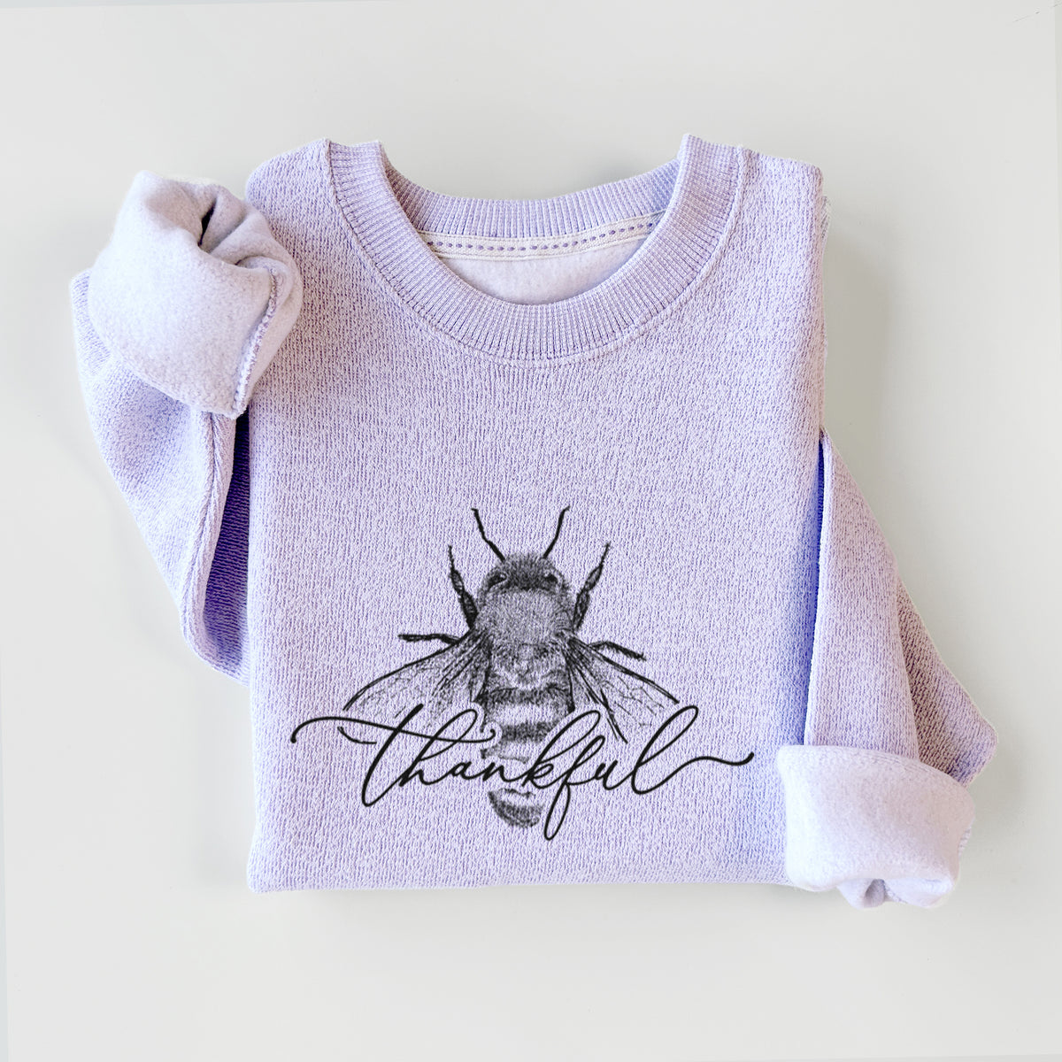 Ice purple knit sweatshirt printed with a black ink bee with the word thankful written in script across it, styled flat.