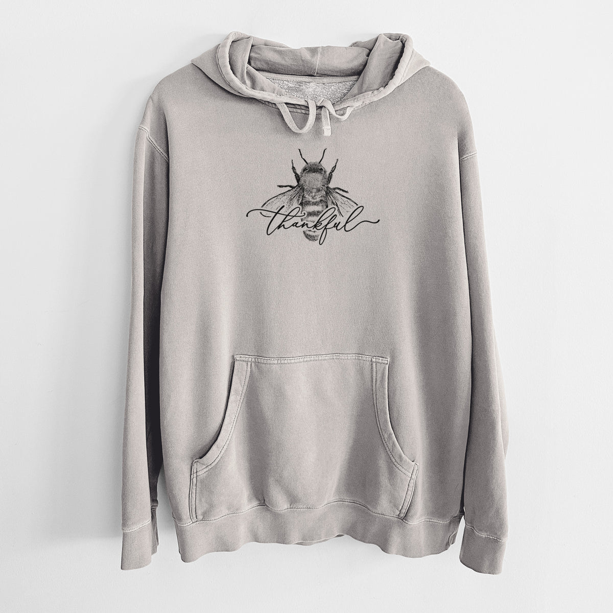 Cement grey pigment dyed hoodie laid flat, printed with a black ink bee with the word thankful written in script across it.