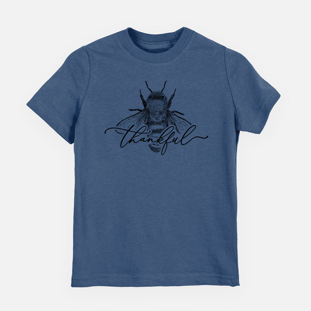 Indigo blue youth t-shirt laid flat, printed with a black ink bee with the word thankful written in script across it.