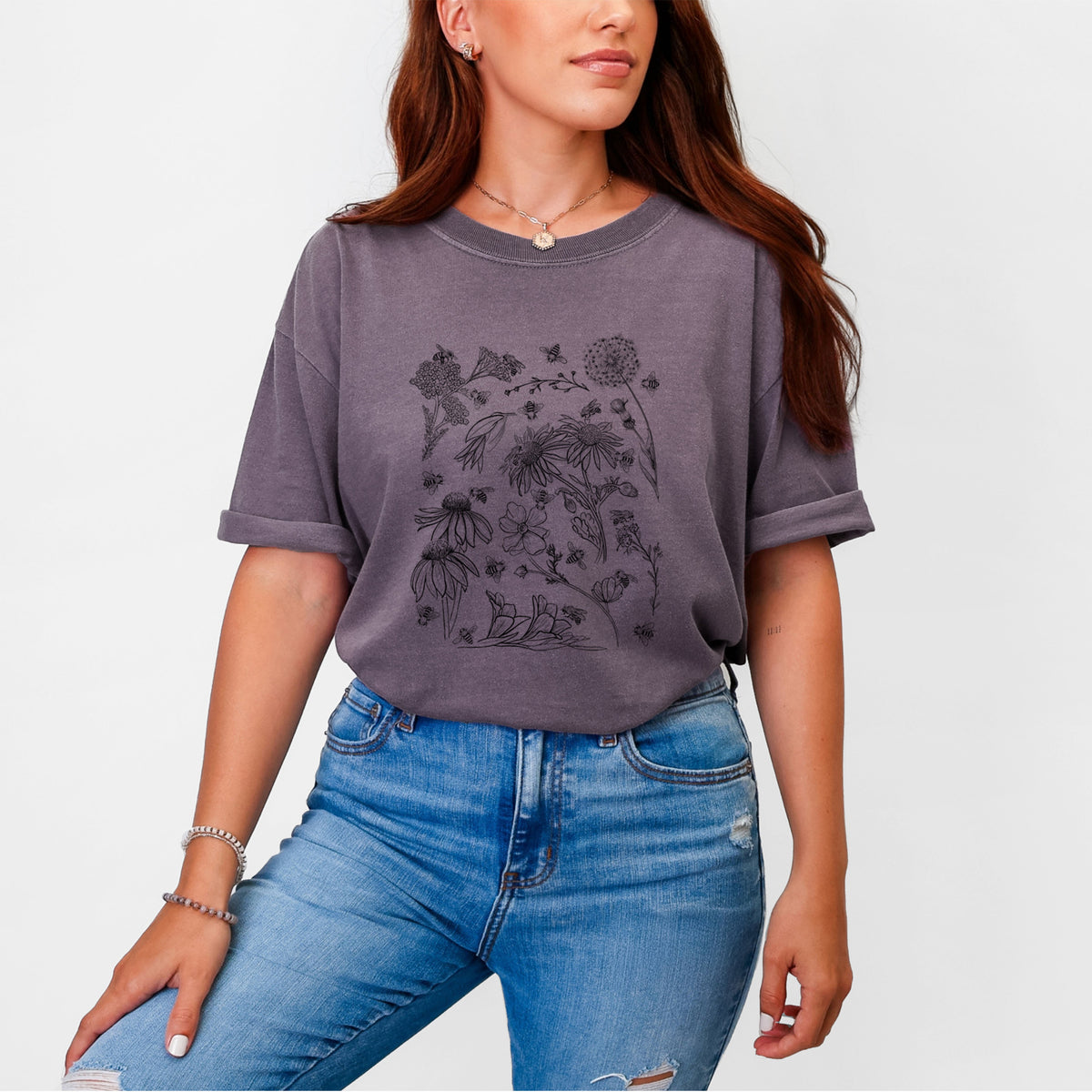 Woman wearing a Comfort Colors t-shirt printed with black ink bees scattered among wildflowers.