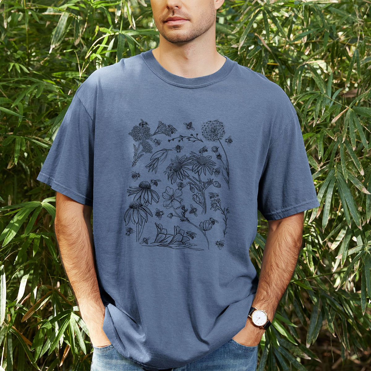 Man wearing a Comfort Colors t-shirt printed with black ink bees scattered among wildflowers, outdoors.