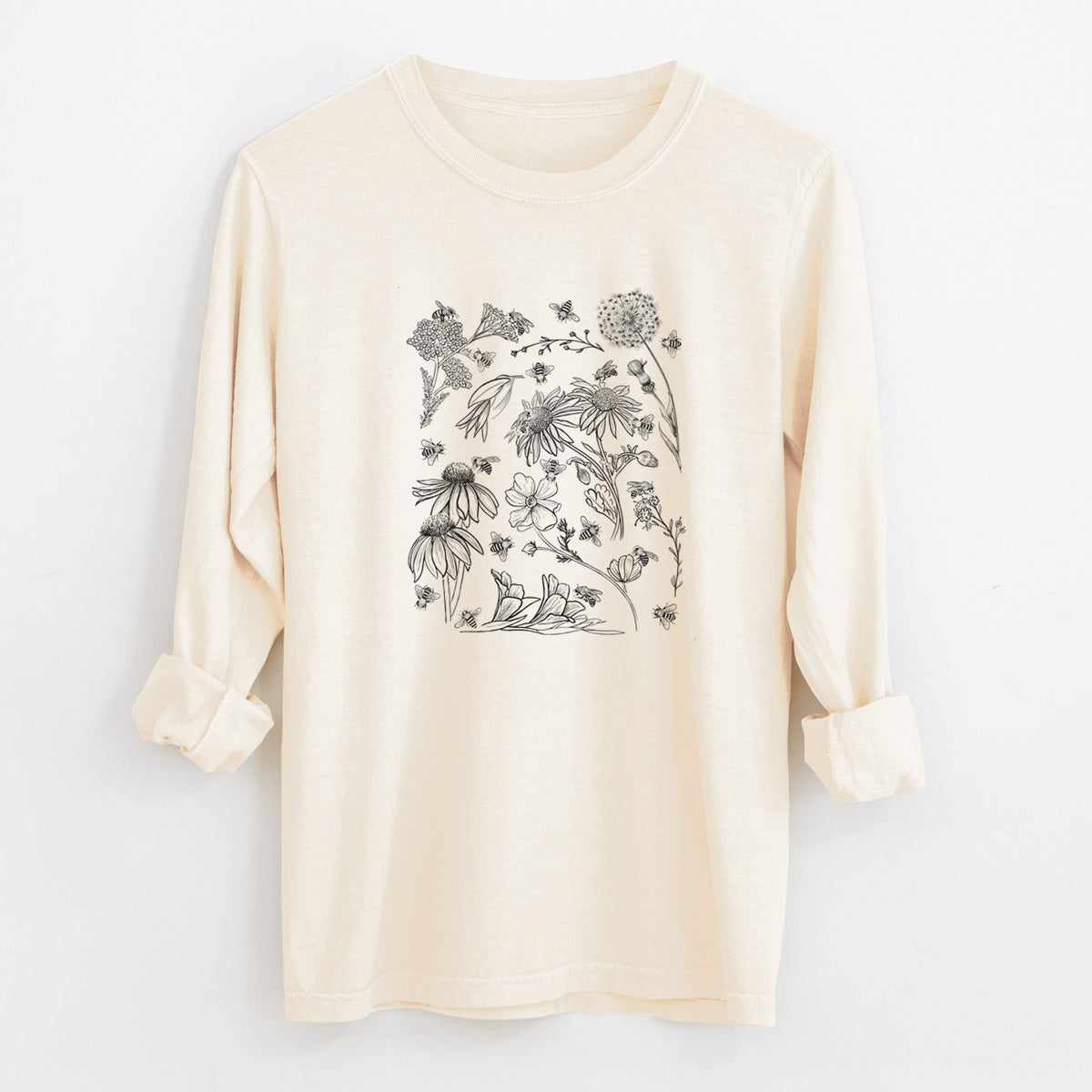 Ivory Comfort Colors long sleeve shirt laid flat with the cuffs rolled, printed with black ink bees scattered among wildflowers.