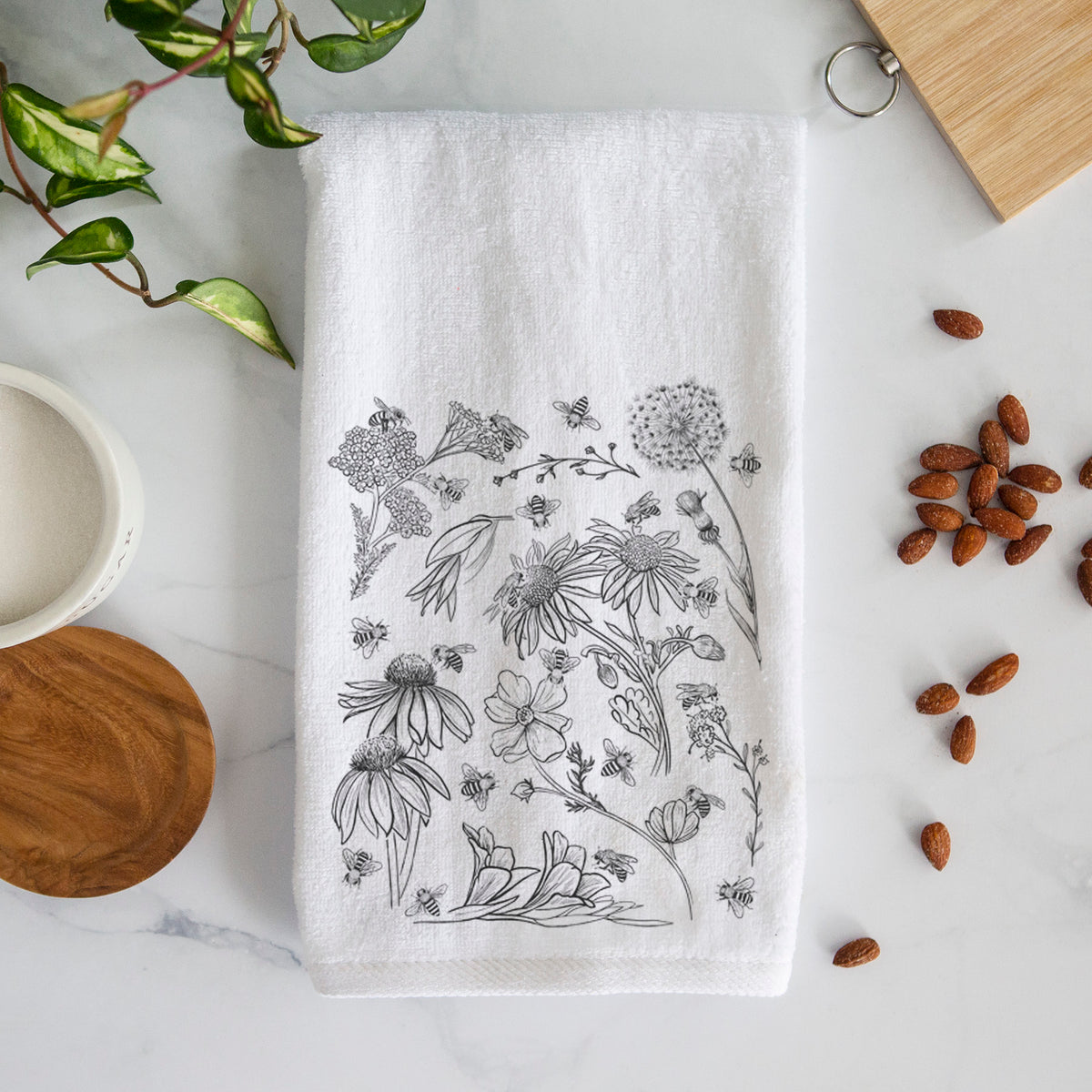 White hand towel printed with black ink bees scattered among wildflowers.