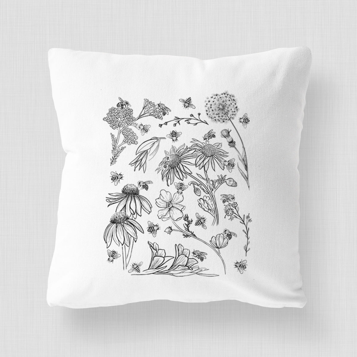 White pillow cover printed with black ink bees scattered among wildflowers.