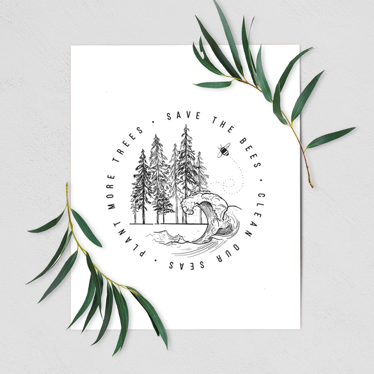 Art print of a circle of pine trees and an ocean wave ringed by the words Save the Bees, Clean Our Seas, Plant More Trees, shown with eucalyptus leaves.