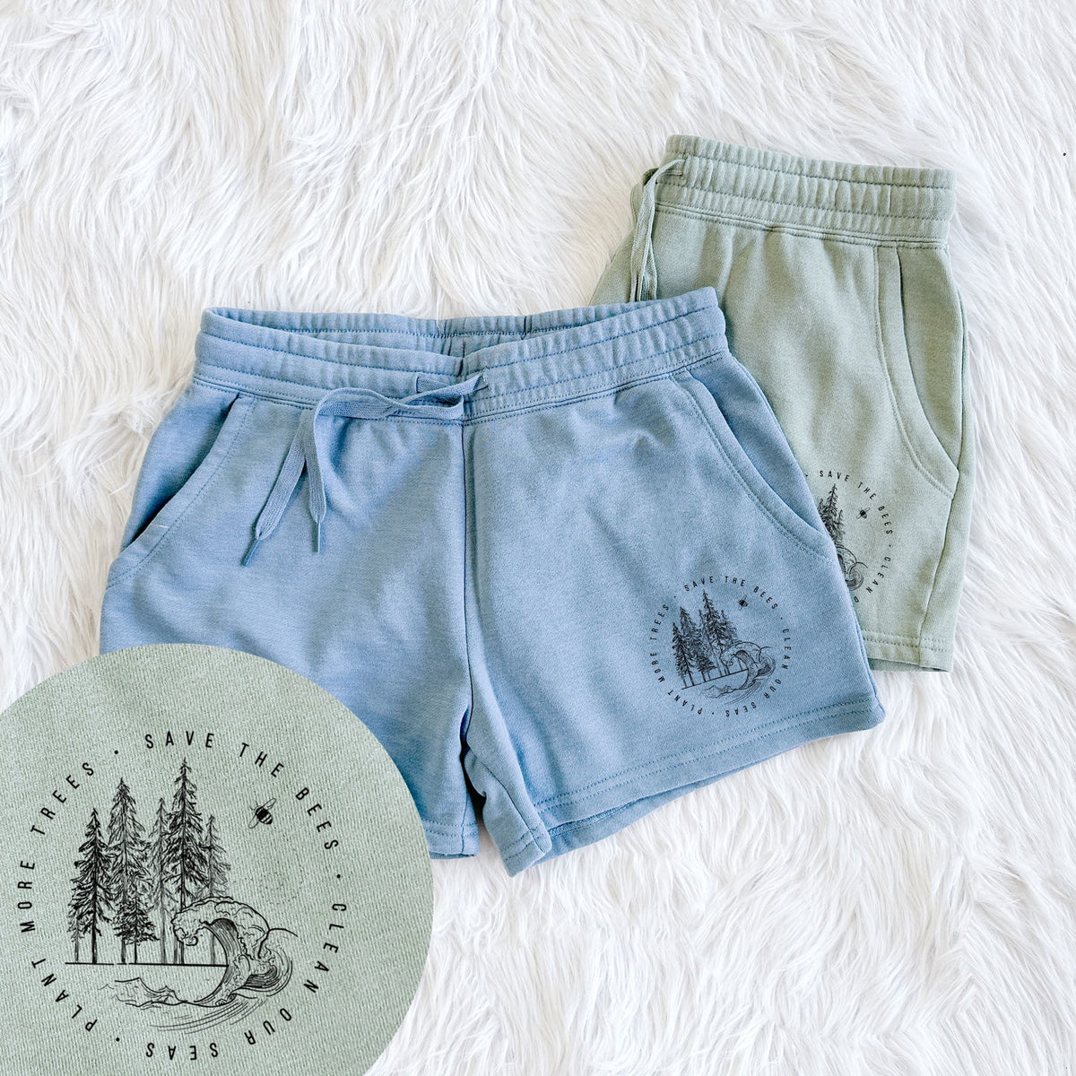 Two pairs of Cali Wave shorts in different colors printed with a circle of pine trees and an ocean wave ringed by the words Save the Bees, Clean Our Seas, Plant More Trees, with a close-up of the print.